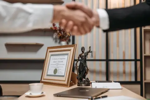 Uścisk dłoni prawników, certyfikat ukończenia i Statua Temidy. Dowiedz się, jak szybko się rozwieść, szukając profesjonalnej pomocy.