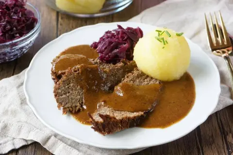 Sauerbraten rezept: Zarte Scheiben Braten in dunkler Sauce, serviert mit Rotkohl und Klößen. Ein Klassiker der deutschen Küche.