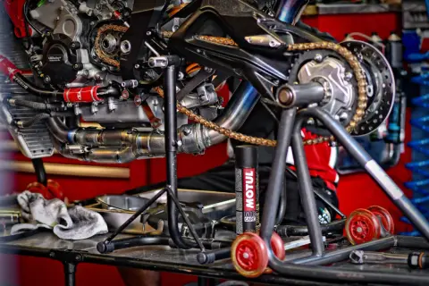 Motocykl na stojaku, gotowy do smarowania łańcucha. Puszka smaru Motul obok.