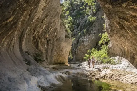 Deux randonneurs explorent les formations rocheuses spectaculaires des concluses de Lussan, un paysage naturel impressionnant.