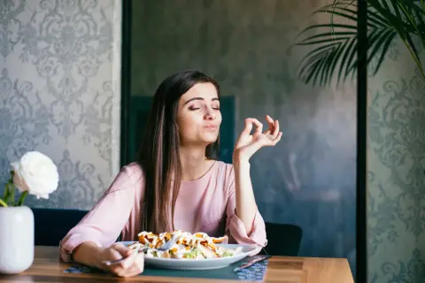Frau genießt ihr Essen, als ob sie OMAD Fasten praktiziert und die einzige Mahlzeit des Tages zelebriert.