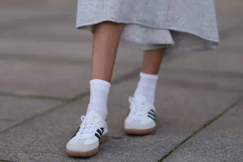 Białe Adidas Samba w stylizacjach z szarą spódnicą i białymi skarpetkami. Klasyka, która zawsze się obroni.