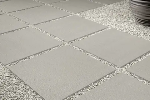 Posa a secco su ghiaia: lastre quadrate grigie alternate a ghiaietto bianco creano un percorso moderno e pulito.