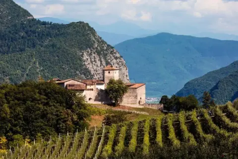 Castello medievale su una collina, circondato da vigneti e montagne, tipico dei paesi Val di Non.