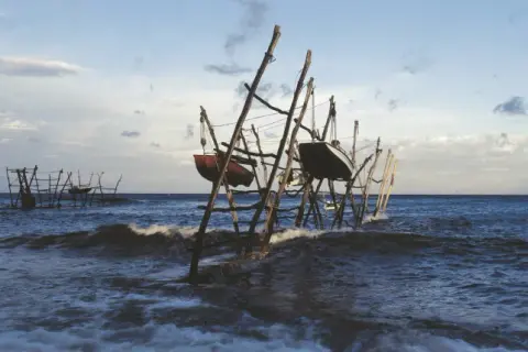 Barcas colgadas en estructuras de madera sobre el mar agitado, un paisaje evocador de lebeche en Rodalquilar.