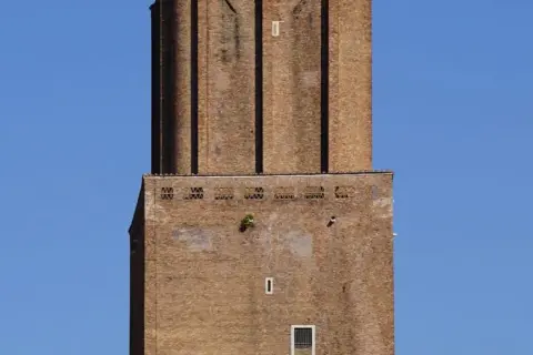 La torre delle Milizie, imponente struttura in mattoni, si staglia contro un cielo azzurro.