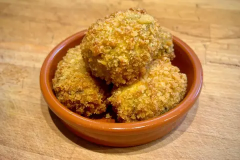 Goldbraune spanische Kroketten, knusprig paniert, in einer Tonschale. Ein leckeres spanische kroketten rezept zum Genießen.