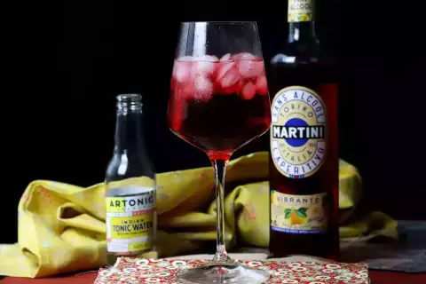Czerwony drink z lodem, obok butelka Martini Vibrante i Artonic Indian Tonic Water. Idealny na letnie popołudnie.