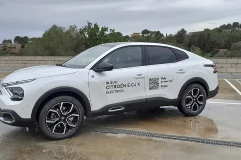 Citroën ë-C4 X eléctrico blanco aparcado en un día nublado. El coche tiene un diseño moderno y elegante.