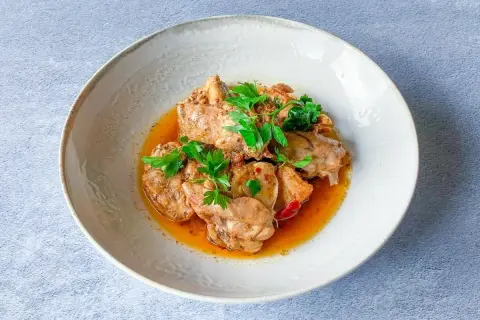 Sabroso conejo en salmorejo, trozos de carne tierna bañados en una salsa rica y aromática, decorado con perejil fresco.