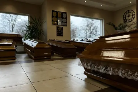 Wnętrze zakładu pogrzebowego z kilkoma drewnianymi trumnami.