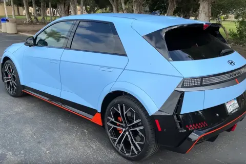 Niebieski Hyundai Ioniq 5 N z czarnymi akcentami i pomarańczowymi detalami stoi na parkingu.