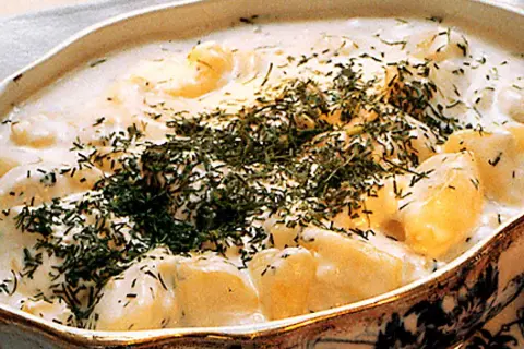 En krämig stuvad potatis med dill, serverad i ett vackert fat. En klassisk svensk rätt som värmer själen.
