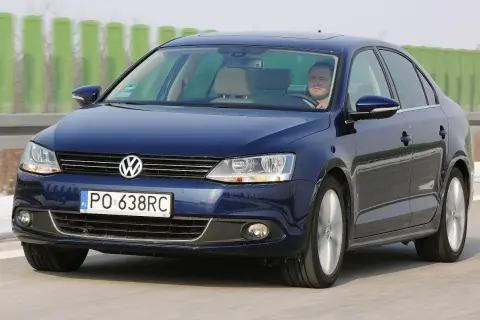 Ciemnoniebieski VW Jetta MK6 jedzie autostradą. Za kierownicą siedzi mężczyzna.