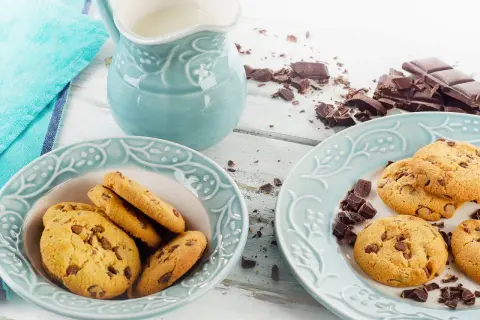 Schokoladenkekse, ein Krug Milch und zerbrochene Schokolade – perfekt für ein leckeres Cookies Rezept.