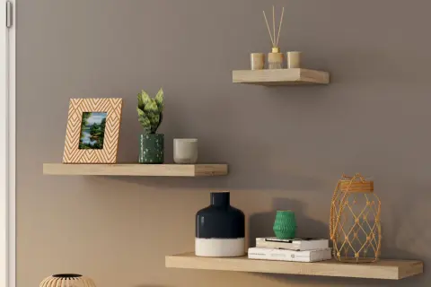 Trois étagères murales en bois clair décorées d'objets : cadre photo, plantes, bougies, vases, livres et diffuseur.