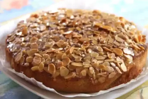 Gâteau aux amandes, doré et croustillant, garni de lamelles d'amandes grillées sur un glaçage brillant.