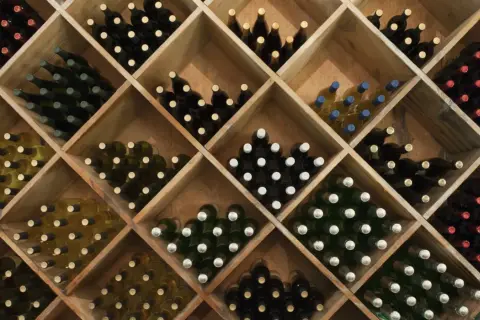 Weinregal mit vielen Flaschen Rotwein und Weißwein. Die Frage, wie lange kann man Rotwein lagern, wird hier durch die Vielfalt der Weine angedeutet.