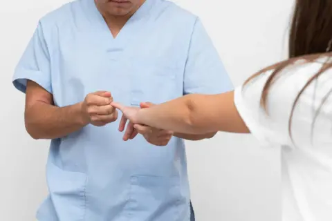 Fizjoterapeuta bada palec pacjentki. Gdy masz wybity palec, do jakiego lekarza się udać?