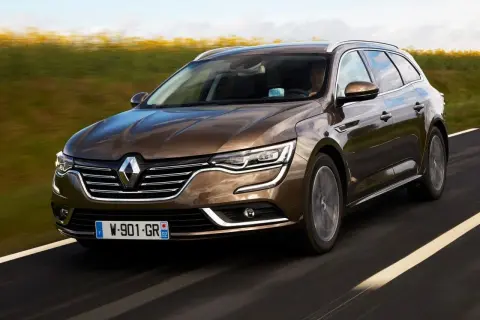 Brązowe renault talisman kombi pędzi po drodze, mijając pola.