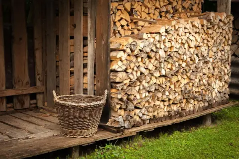 Ein Korb steht neben einem Holzstapel, bereit, das Holz im Ofen zu trocknen.