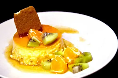En krämig creme caramel med frukt och en kexbit. Perfekt för ett somrigt recept.