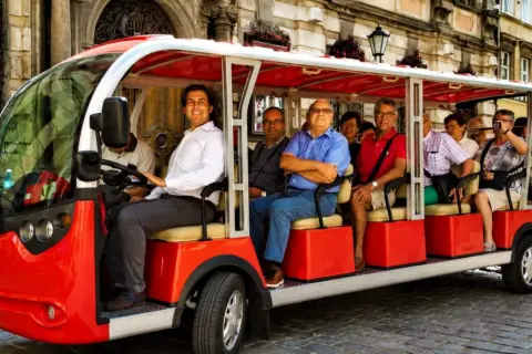 Eine Gruppe von Touristen genießt eine entspannte Stadtrundfahrt in Breslau mit einem roten Elektro-Tourbus.
