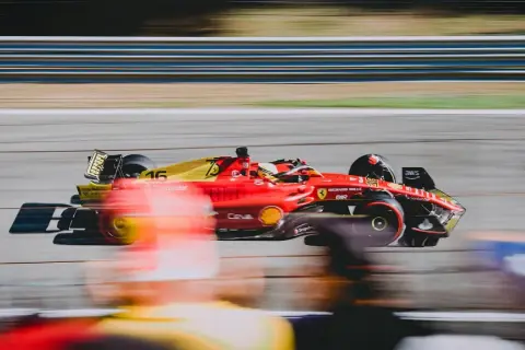Czerwono-żółty bolid Ferrari z numerem 16 pędzi po torze. Zastanawiasz się, ile trwa wyścig F1? To zależy od wielu czynników, ale zawsze jest to ekscytujące widowisko!