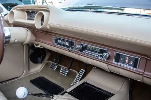 Armaturenbrett eines Oldtimers mit altem Autoradio. Mit einem Adapter lässt sich das alte Autoradio mit dem Handy verbinden, um Musik zu hören.