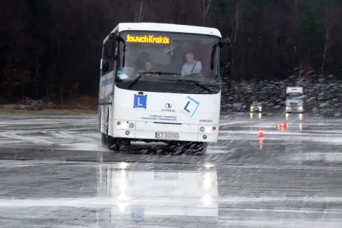 Autosan Lider Midi na mokrym placu manewrowym, z widocznymi kierowcami w kabinie.