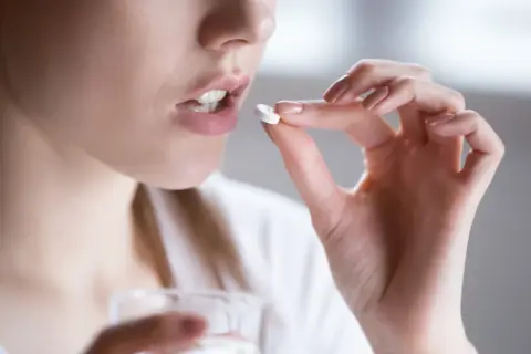 Kobieta bierze tabletkę clindamycin na ból zęba.