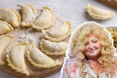 Magda Gessler prezentuje przepis na ciasto na pierogi. Na zdjęciu surowe pierogi na desce i uśmiechnięta restauratorka.
