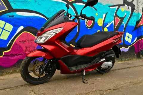 Czerwony skuter Honda PCX 125 na tle kolorowego graffiti. Mimo że jest to niezawodny model, warto pamiętać o jego awaryjności w ekstremalnych warunkach.