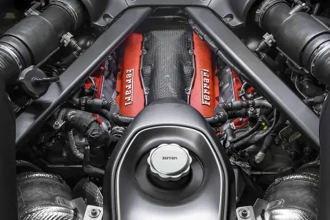 Silnik Ferrari v12, z czerwonymi pokrywami zaworów i charakterystycznym logo, gotowy do pracy.