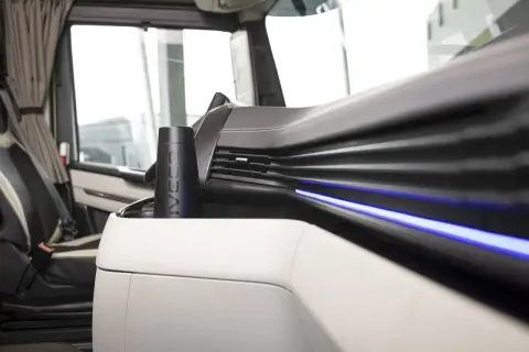 Un porte-gobelet noir avec le logo IVECO, un des indispensables du routier, est placé sur la console centrale d'un camion.