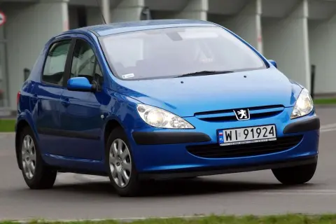 Niebieski Peugeot 307 2.0 HDI z polskimi tablicami WI 91924 jedzie po drodze.