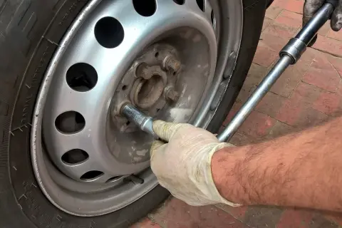 Main tenant utilise une clé pour changer un pneu.