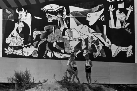 Dzieci bawią się przed monumentalnym obrazem Guernica.