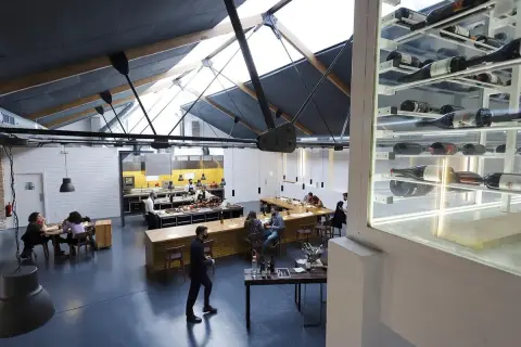 Interior de un restaurante con cocina abierta y estanterías de vino. Un lugar ideal para disfrutar de una experiencia Bib Gourmand en Zaragoza.