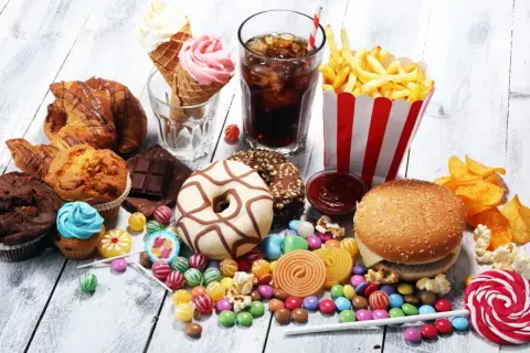 En överflöd av ultraprocessad mat: hamburgare, pommes frites, donuts, godis, glass, läsk och bakverk.
