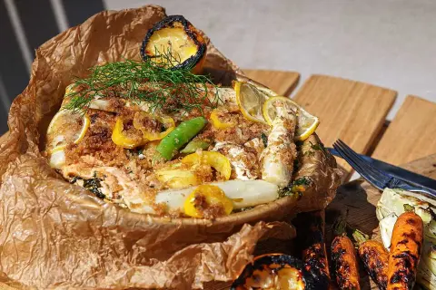 Fisk i folie med citron, dill och grönsaker, serverad med grillade morötter och fänkål.