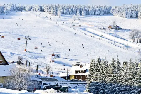 Stok narciarski w Karkonoszach, idealne miejsce na ferie zimowe 2026 dolnośląskie. Narciarze szusują po ośnieżonych zboczach, a kolejki linowe wwożą ich na szczyt.