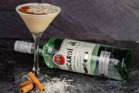 Koktajl z wiórkami kokosowymi i cynamonem, obok butelka Bacardi Carta Blanca. Idealny sposób, jak pić Bacardi!