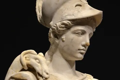 Buste en marbre d'Athéna, déesse guerrière, portant un casque orné d'un serpent. La sculpture, d'une grande finesse, capture la noblesse de la déesse.
