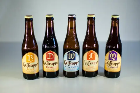 Cinque bottiglie di birra La Trappe, tra cui Blond, Dubbel, Witte Trappist, Tripel e Quadrupel, disposte in fila.