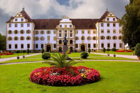 Prachtvolles Schloss Salem mit symmetrischer Fassade, gelben Akzenten und einem gepflegten Garten voller Blumen und Bäume.