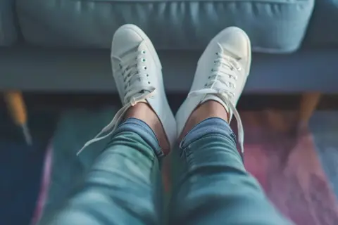 Vita sneakers sitter bekvämt på fötterna, med snören löst knutna. Perfekt för att visa hur skor ska sitta för maximal komfort.