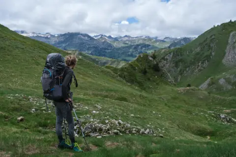 Randonneuse avec un grand sac à dos, prête à explorer les montagnes. Un guide pour comment choisir son sac de randonnée.