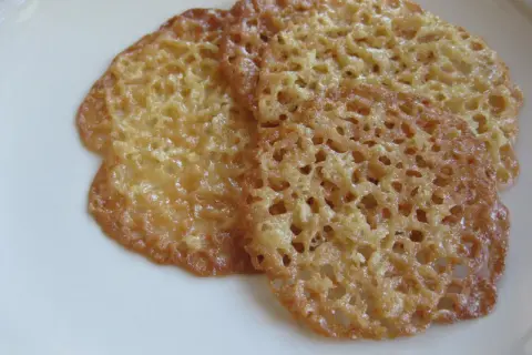 Tre gyllene havreflarn ligger på en vit tallrik. Dessa spröda kakor är perfekta för ett enkelt havreflarn recept.