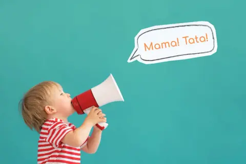 Mały chłopiec w czerwono-białej koszulce krzyczy przez megafon: "Mama! Tata!".